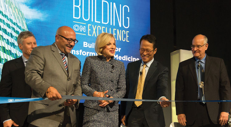 BWH President and staff cutting a ribbon in front of a presentation screen